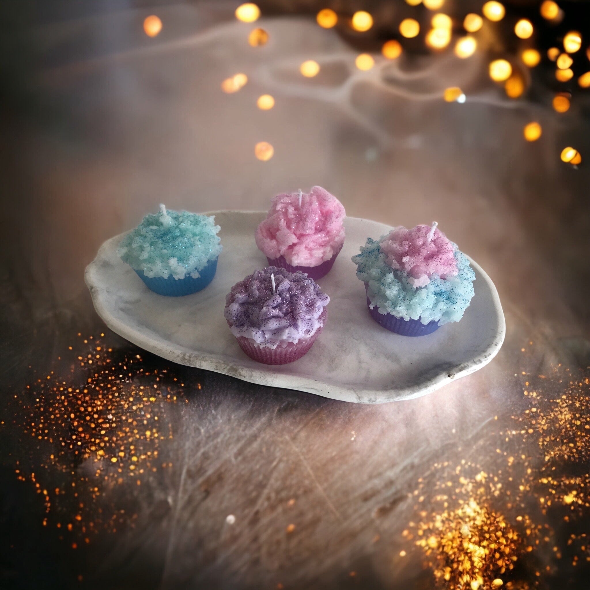 Kerzen in Muffinform verschiedene Farben auf Tablett dekoriert.