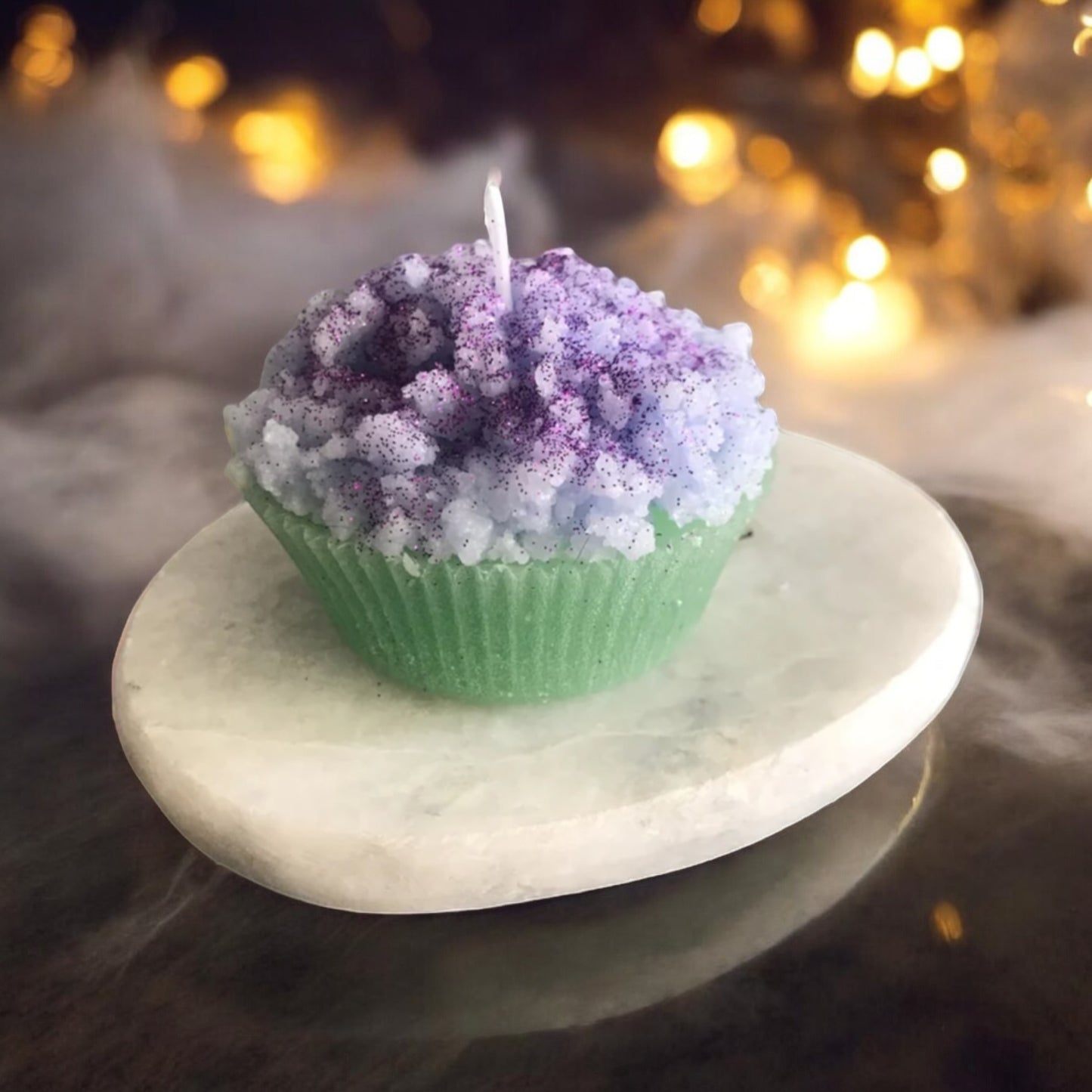 Handgefertigte Muffin-Kerze in Grün mit lila Topping, auf einer eleganten Steinplatte. Perfekt als stilvolle Geschenkidee oder Deko für besondere Anlässe.